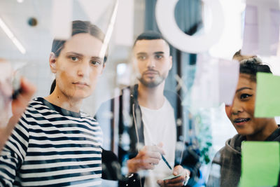 Young multi-ethnic hackers discussing strategy over glass during meeting at creative office