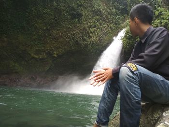 Rear view of man looking at waterfall