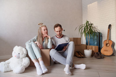 Young couple holding clipboard sitting in cardboard box