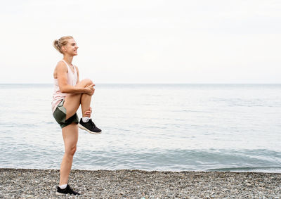 Young woman standing on beach against sky