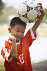 Portrait of confident boy with soccer ball gesturing on field at park