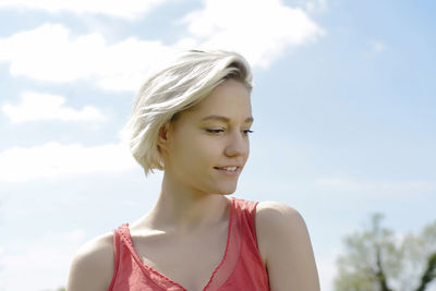 Beautiful young woman looking down against sky