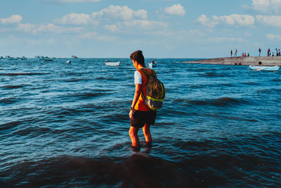 Rear view of man standing on beach against sky
