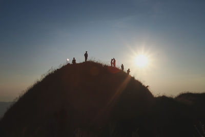 Silhouette people on mountain against sky during sunset