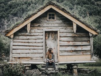 Full length of woman sitting outside house