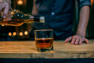 Midsection of man pouring wine in glass on table