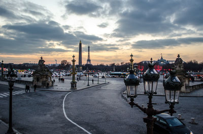 Cars on road against buildings at sunset