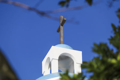 Low angle view of cross and building against blue sky