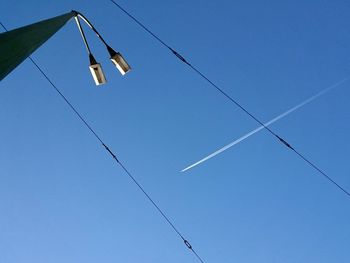 Low angle view of vapor trails in blue sky