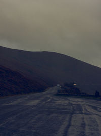 Road leading towards mountain against sky