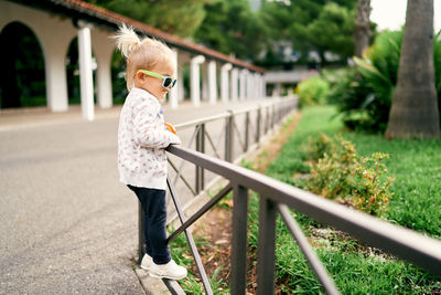 Full length of young woman standing on railing