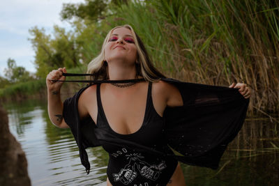 Portrait of young woman standing against lake