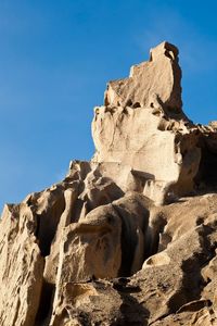 Low angle view of rock formation against clear blue sky