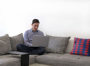 Man using laptop while sitting on sofa at home