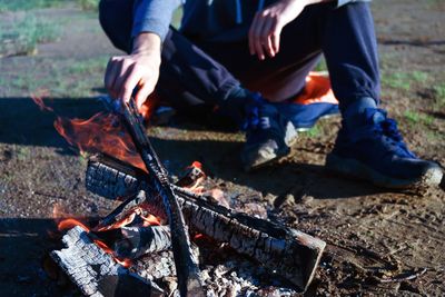 Low section of man sitting by campfire on land