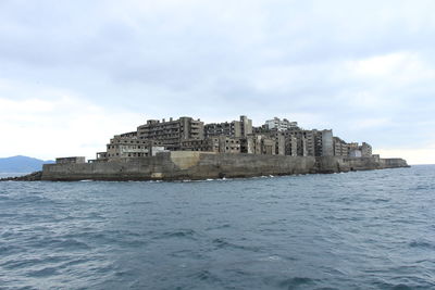 Scenic view of hashima island against cloudy sky