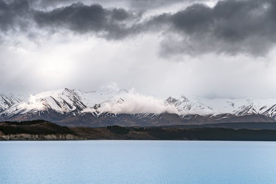 Gloomy landscape of new zealand southern alps and lake pukaki with blue sky and clouds.