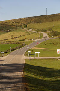 Road amidst field against sky