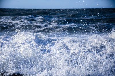 Waves splashing on sea against sky