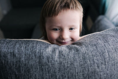 Kid toddler builds house from pillows on sofa in living room, lifestyle and games in real interior