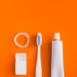 Close-up of toothbrush with toothpaste over orange background