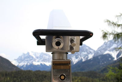 Close-up of coin-operated binoculars against mountain range against sky