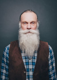 Portrait of confident senior man with long white beard over gray background