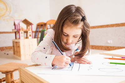 Portrait of girl holding table against wall