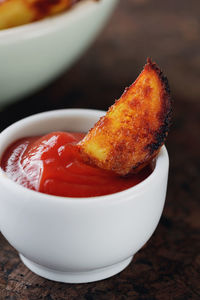 Close-up of fried potato and sauce in bowl on table
