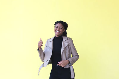 Portrait of smiling young woman against gray background