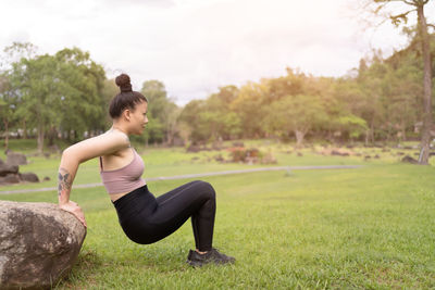 Side view of woman exercising on field
