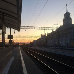 Railroad station platform against sky at sunset