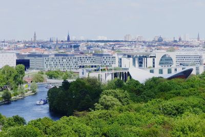 Trees and buildings in city against sky