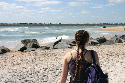 Rear view of woman at beach against sky