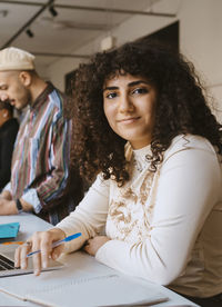 Portrait of young woman with curly hair sitting at community college