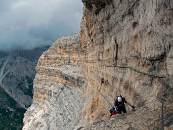 Full length of man climbing on cliff against sky