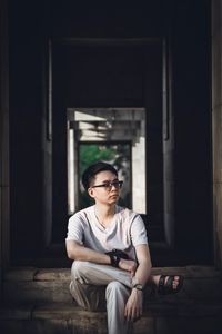 Young man looking away while sitting on staircase