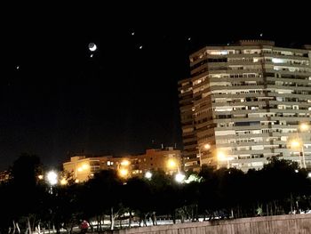 Illuminated buildings against sky at night