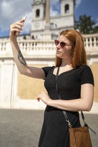 Fashion red hair woman with sunglasses looking at phone taking selfie
