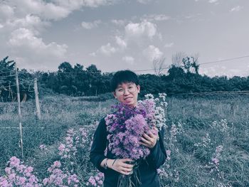 Portrait of smiling woman standing on purple flowering plants