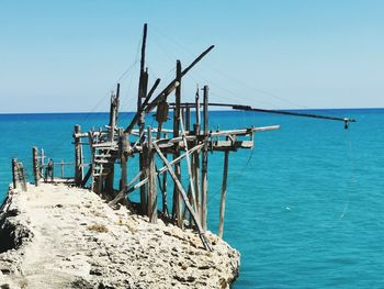 Wooden posts on beach against clear sky