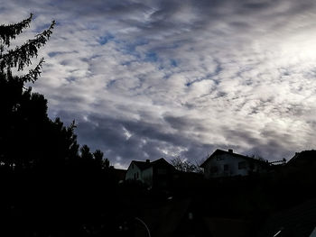 Low angle view of silhouette trees and buildings against sky