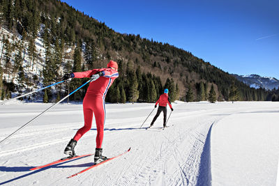 Rear view of men skiing on field against mountain
