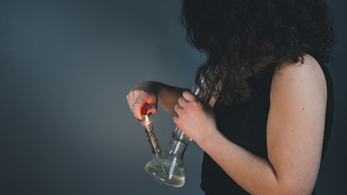 Midsection of woman smoking hookah against white background