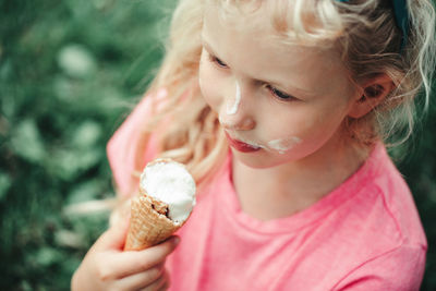 Cute funny girl with dirty nose and milk moustaches eating licking ice cream from waffle cone