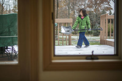 A small boy helping shovel snow on a patio in winter