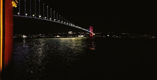 Illuminated bridge over river at night