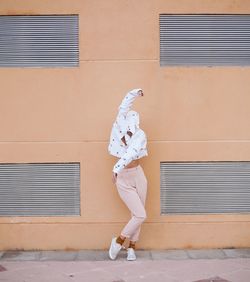 Side view of woman standing against building