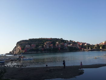 People on beach against clear sky