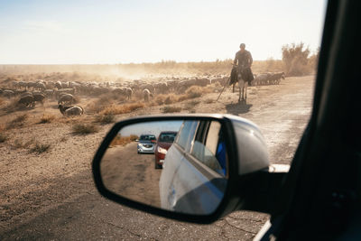 Reflection of man on side-view mirror